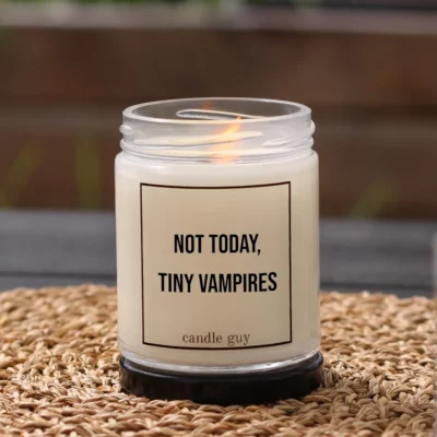 Burning anti-mosquito candle with the quote “Not today, tiny vampires” in a white jar in a cozy setting