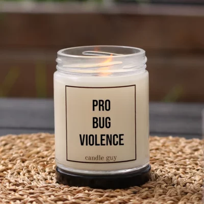 Burning anti-mosquito candle with the quote “Pro Bug Violence” in a white jar in a cozy setting